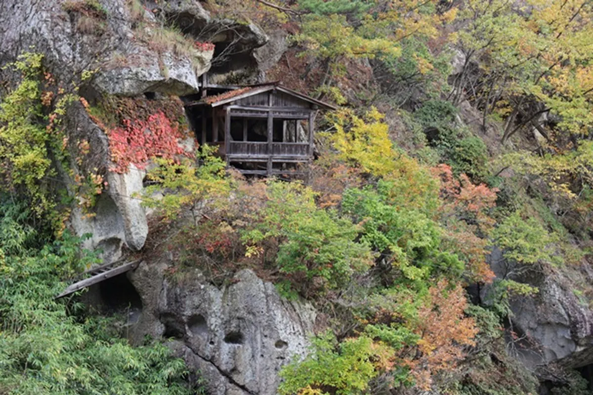 Yamadera temple hall on a cliff with autumn leaves
